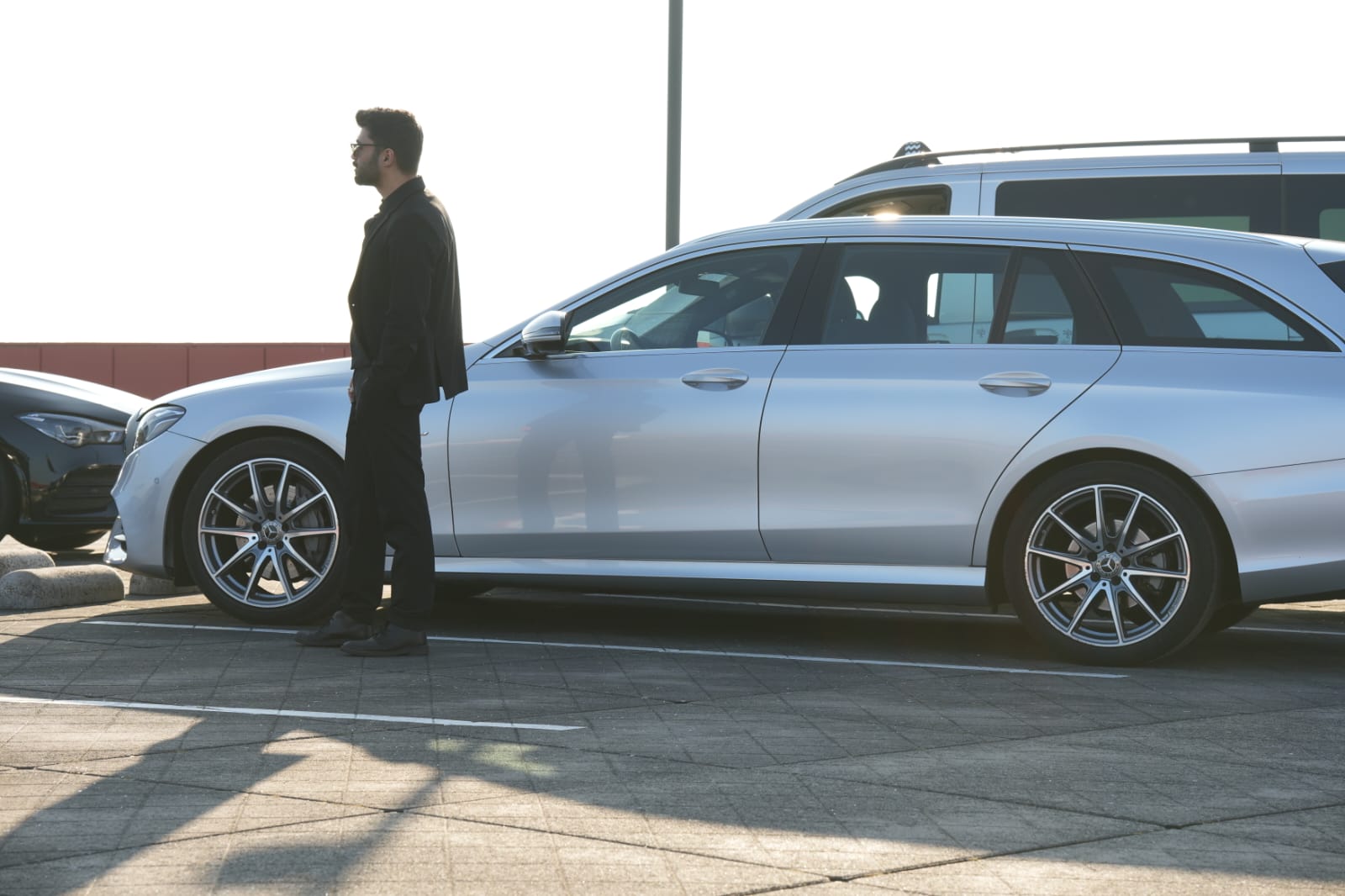 Silver Mercedes parked with a person standing beside it